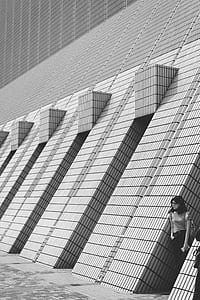 grayscale photo of woman leaning on wall thumbnail