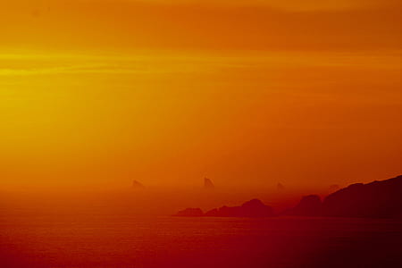 silhouette of mountains near shoreline at golden hour thumbnail