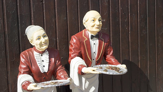 female and male chef holding tray filled with coin figurines thumbnail