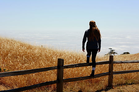 woman standing on brown wooden fence near field thumbnail