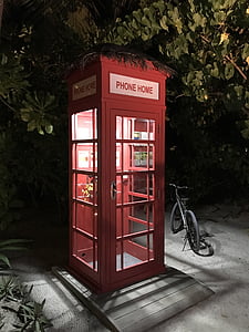 red telephone booth beside black bicycle at nighttime thumbnail