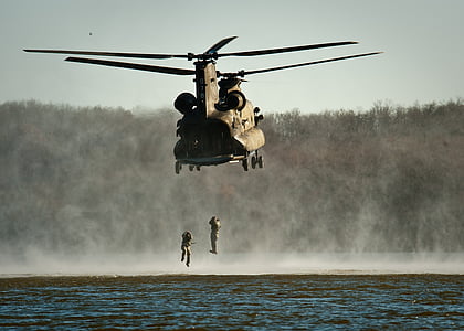 two soldiers hanging under brown helicopter during daytime thumbnail