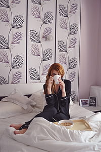 woman wearing piping-white black pajama set holding white ceramic mug sitting on white bedspread set thumbnail