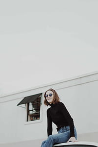 woman in black long-sleeved turtleneck top sits smiles near house thumbnail