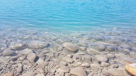 gray stones under blue water at daytime thumbnail