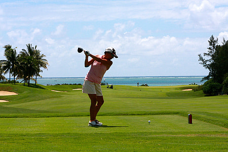 woman in pink tank top with matching white shorts playing a golf under the blue sky during daytime thumbnail