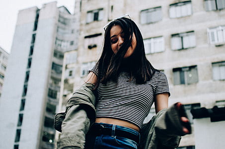 woman wearing black and grey stripe shirt standing near the building thumbnail