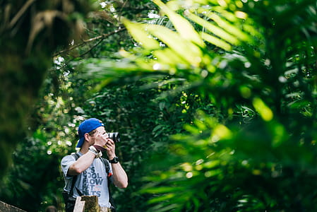 selective focus photo of man taking photo view from behind the bush thumbnail