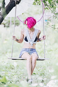 woman sits on wooden swing on tree during daytime thumbnail