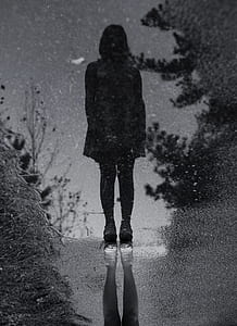silhouette of woman standing on body of water in grayscale photography thumbnail