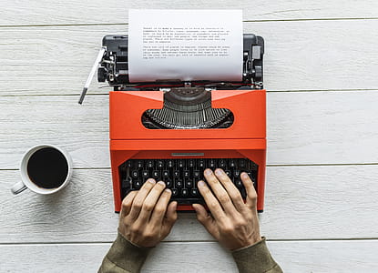 Person Holding Black and Orange Typewriter thumbnail