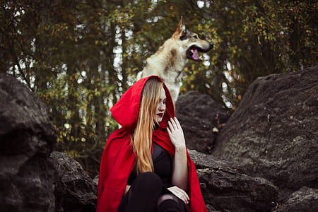 woman in Red Riding Hood costume sitting on black rock thumbnail