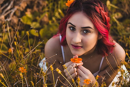 woman holding orange petaled flower during daytime thumbnail