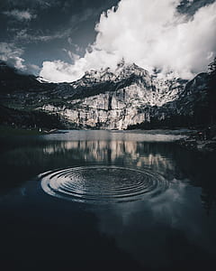 shallow focus photography of water drop in body of water in front of snowy mountain thumbnail