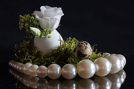 close-up photo of beaded necklace, egg, and white flower thumbnail