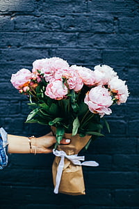 bouquet of pink roses hold one handed by the blue brick wall thumbnail