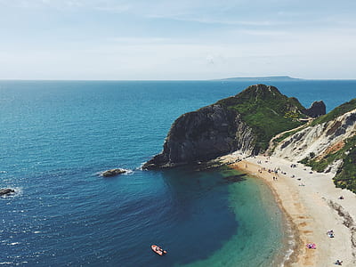 aerial view of beach with mountain and blue ocean thumbnail