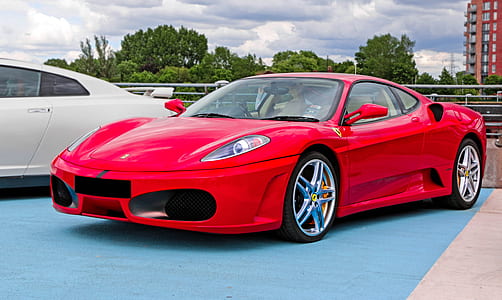 red Ferrari sports coupe beside white car during daytime thumbnail