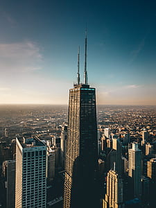 high-rise curtained wall building surrounded by other buildings under blue sky at daytime thumbnail