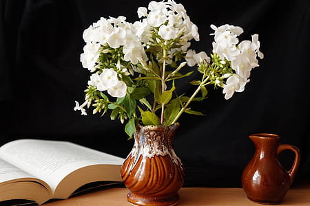 two brown ceramic vases on beige wooden surface beside opened white book thumbnail