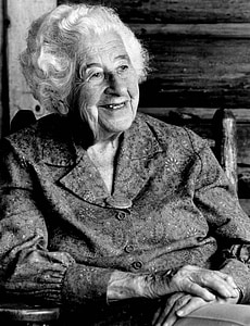 grayscale photo of woman sitting on chair thumbnail