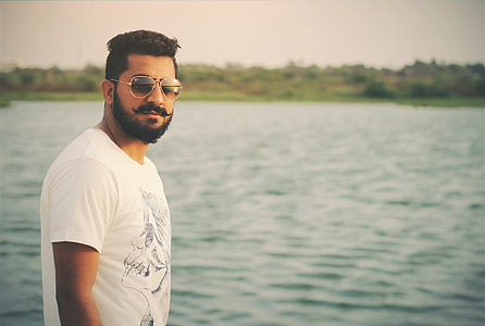 man wearing white crew-neck shirt near body of water at daytime thumbnail