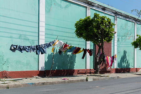 assorted-color clothes lot hanging beside teal building thumbnail