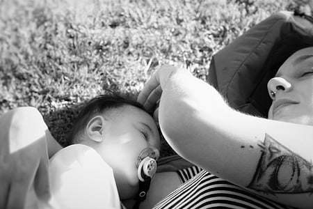 grayscale photo of woman and toddler lying on sand thumbnail