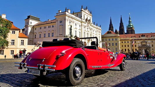 classic red sedan convertible near white building at daytime thumbnail