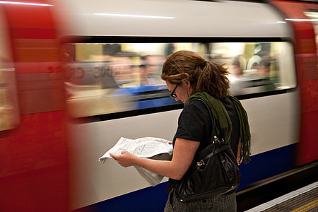 A woman reads the newspaper as she waits for her connection on the London Underground thumbnail