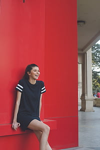 laughing woman leaning against concrete wall thumbnail