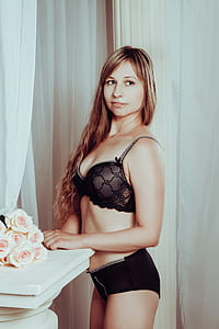woman in black lace bra and pantie standing with hand near bouquet of flowers thumbnail