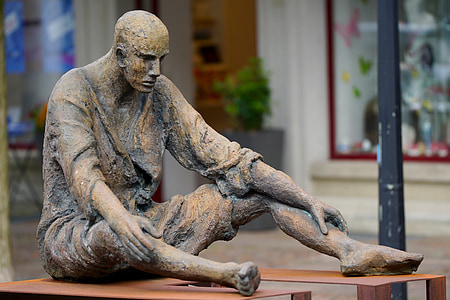 man sitting on brown bench statuette thumbnail