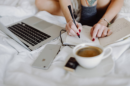 Woman working on a laptop while enjoying a breakfast coffee and chocolate in bed thumbnail