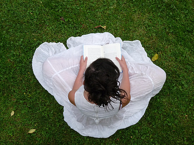 woman in white dress sitting on green grass while reading books during daytime thumbnail