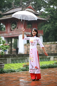 woman in white, red, and orange traditional dress holding up umbrella thumbnail