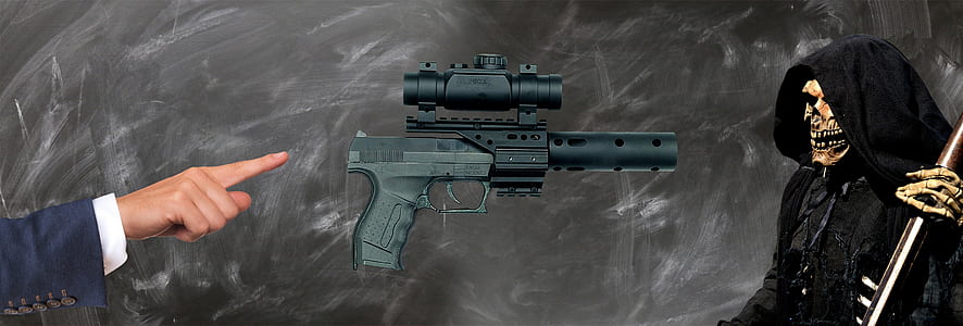 person pointing at pistol facing hooded figure thumbnail