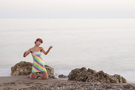 woman kneeling while closing eyes in seashore at daytime thumbnail