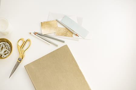 yellow shears near paper on white surface thumbnail