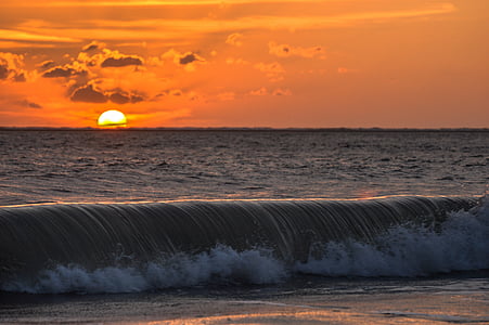 seawaves on shore against golden sun thumbnail