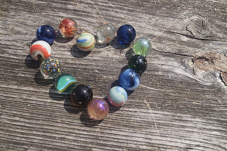 assorted toy marbles on beige wooden surface thumbnail