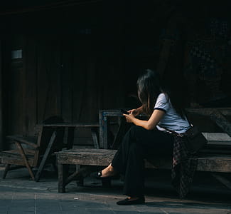 Woman Wearing White Crew-neck Shirt Sitting on Brown Wooden Bench thumbnail