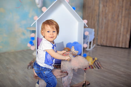 toddler wearing white and blue riding brown animal toy thumbnail