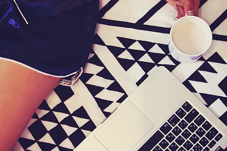 close up photo of gray laptop computer and person holding white ceramic mug thumbnail