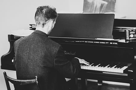 grayscale photo of man playing grand piano thumbnail