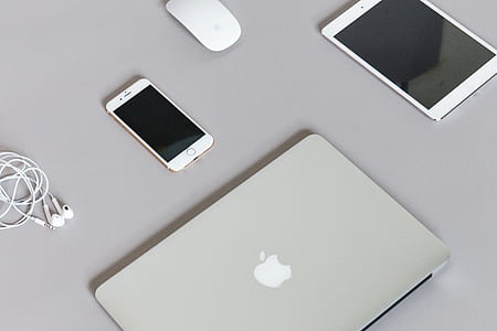 Apple magic mouse, iPhone 6. iPad, and silver MacBook on table thumbnail