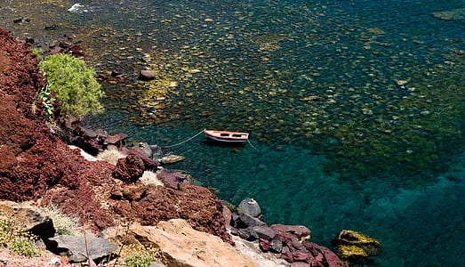 aerial view photography of jon boat beside rock thumbnail