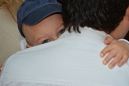 baby wearing black cap hugging man thumbnail
