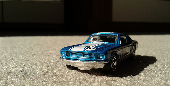 blue Ford Mustang coupe scale model toy on brown surface thumbnail