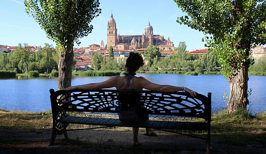 woman sitting on bench in front of body of water thumbnail